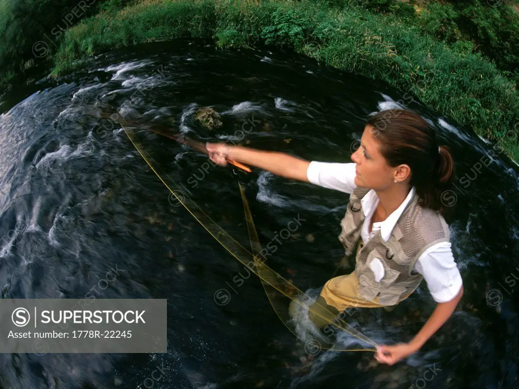 Twenty_year_old woman casting her fly_fishing rod while standing in a stream.