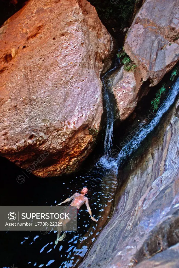 A man floating on his back near a waterfall, Grand Canyon, Arizona.