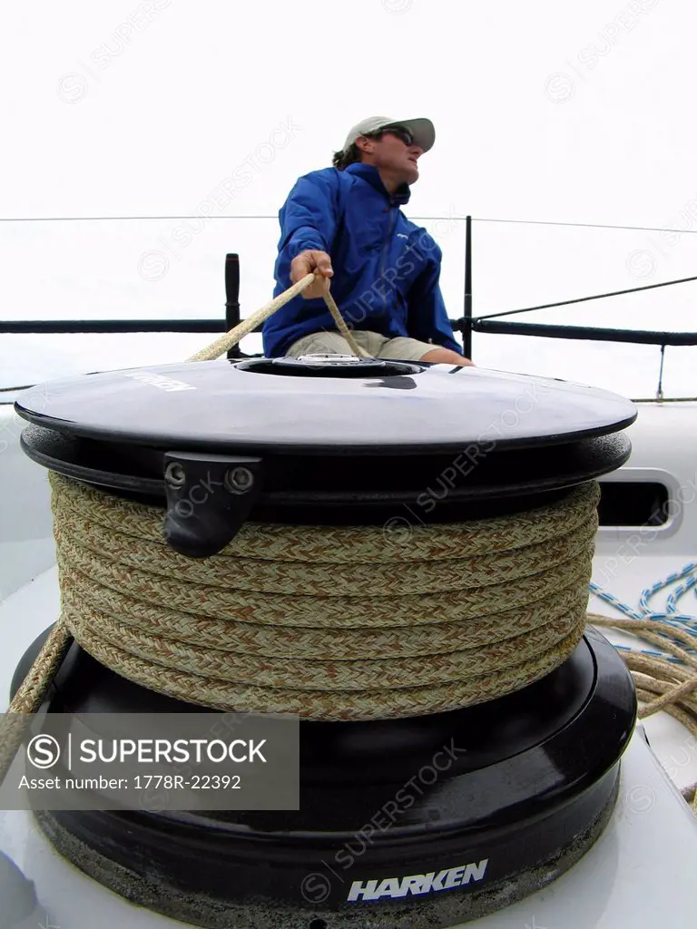 Sailor trimming the main sail of a racing yacht