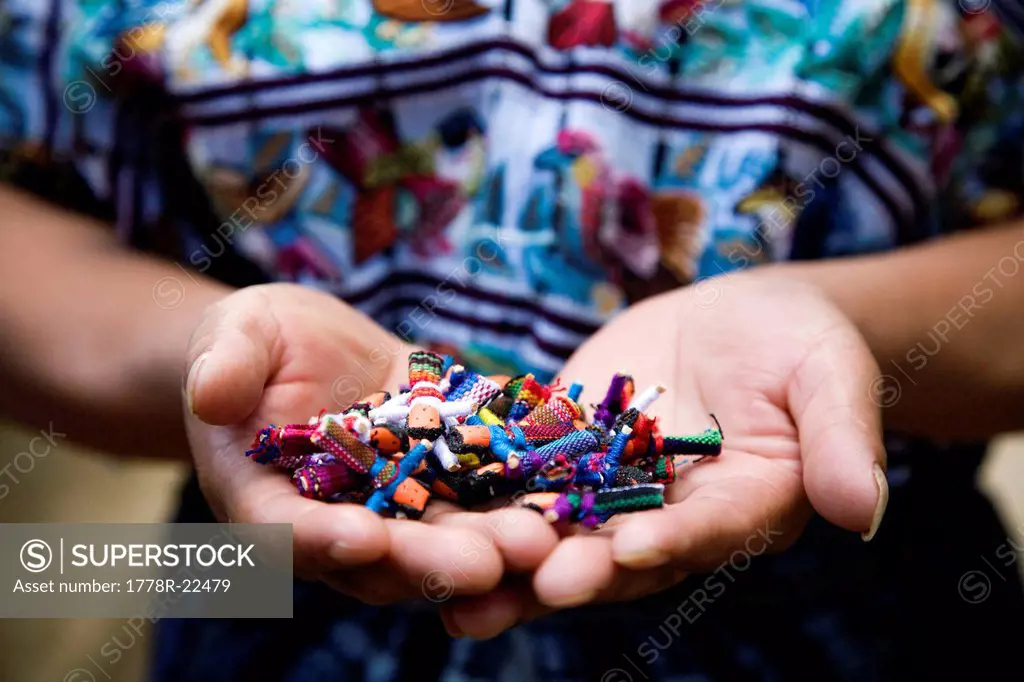 A woman holds a collection of prayer dolls she made in her house with the support of a local co_op.