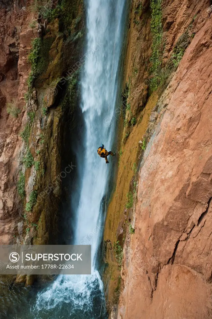Man rappelling down next to a waterfall, Grand Canyon, Arizona.