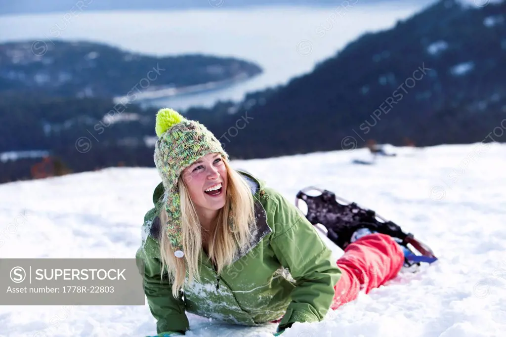 A athletic young woman laughs while snowshoeing in Idaho.