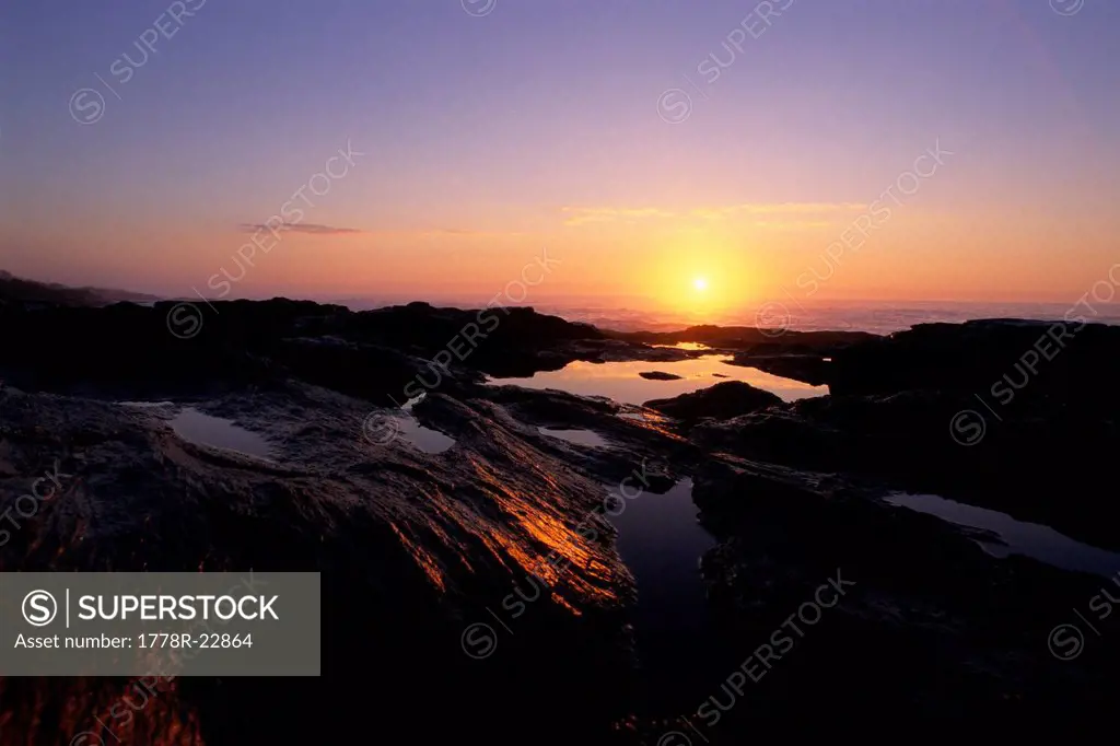 Sunrise over the Atlantic Ocean reflects in tidal pools at Two Lights State Park near Portland, ME
