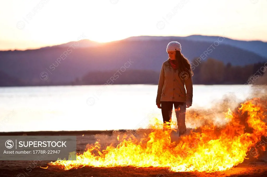A woman standing next to raging flames and a lake in Idaho.