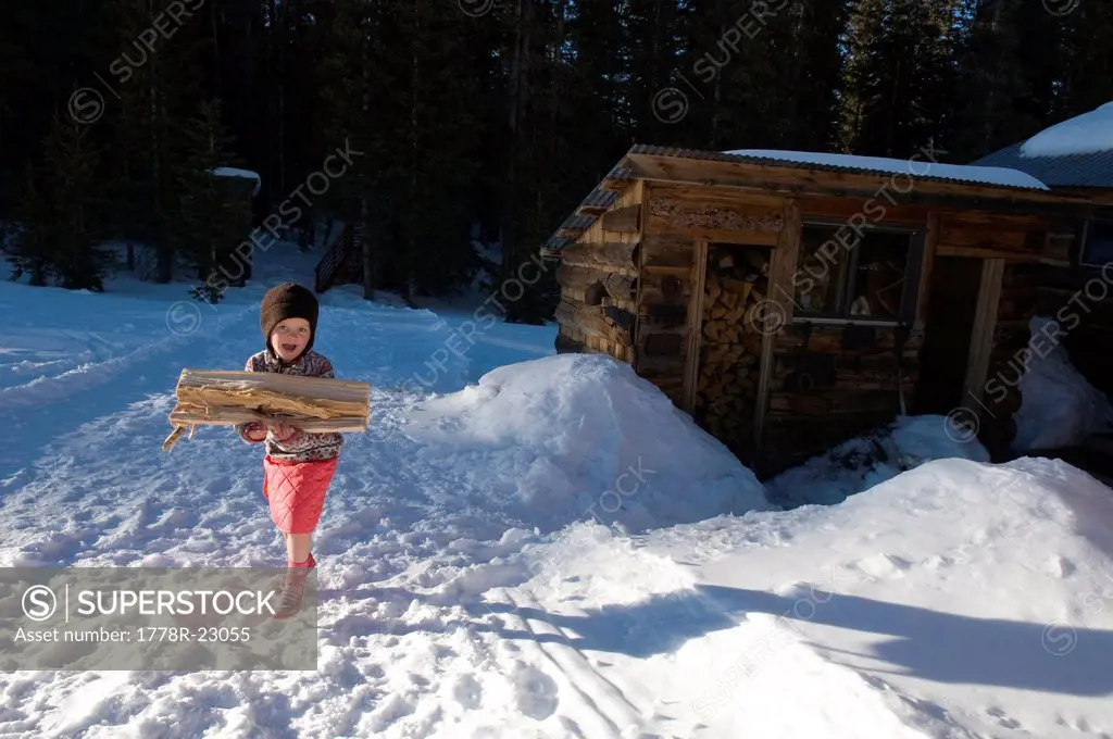 Young girl carrying firewood from shed, Lizard Head Pass, Telluride, Colorado.