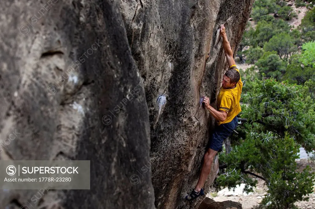 A man crimps hard while stretched out on a boulder problem at Joes Valley Utah.