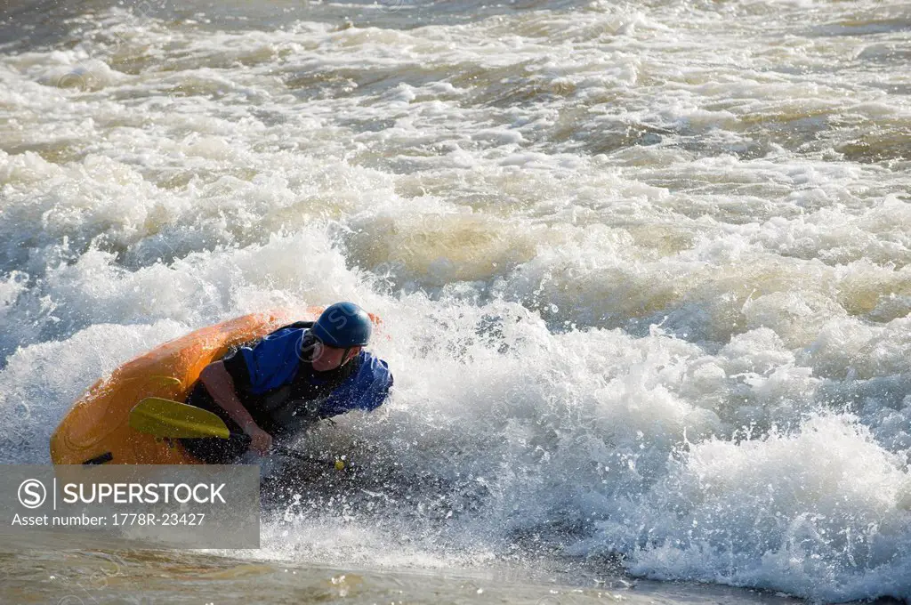 A male whitewater kayaker plays on the Missoula play wave.