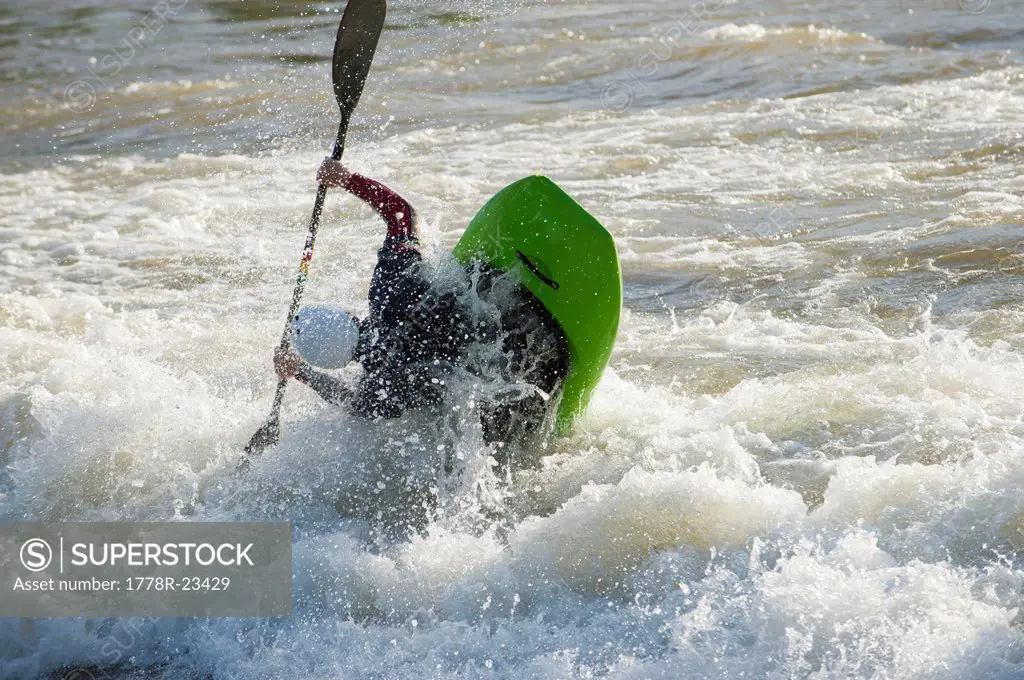 A male whitewater kayaker playboats on the Missoula play wave on the Clark Fork River, Missoula, Montana.
