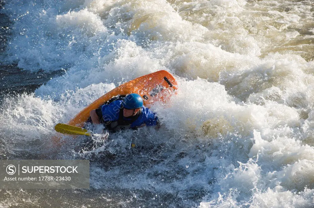 A male whitewater kayaker playboats on the Missoula play wave in the Clark Fork River, Missoula, Montana.