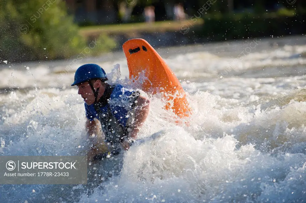 A male whitewater kayaker playboats on the Missoula play wave.