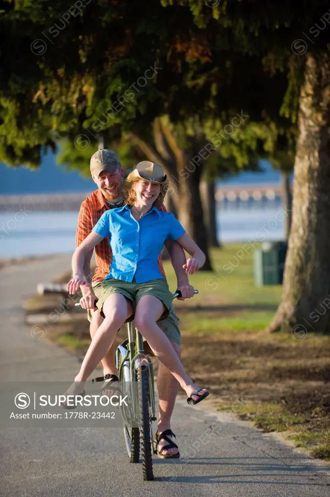 A young woman rides on the handle bars of a young man´s cruiser bike in Sandpoint, Idaho.