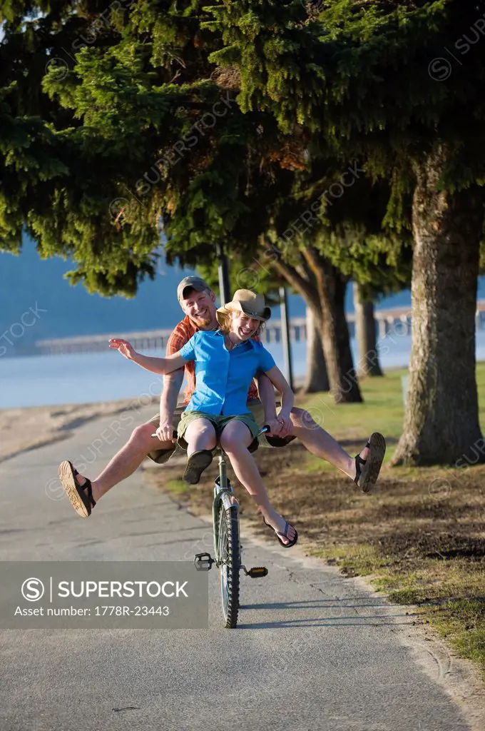 A young woman rides on the handle bars of a young man´s cruiser bike in Sandpoint, Idaho.