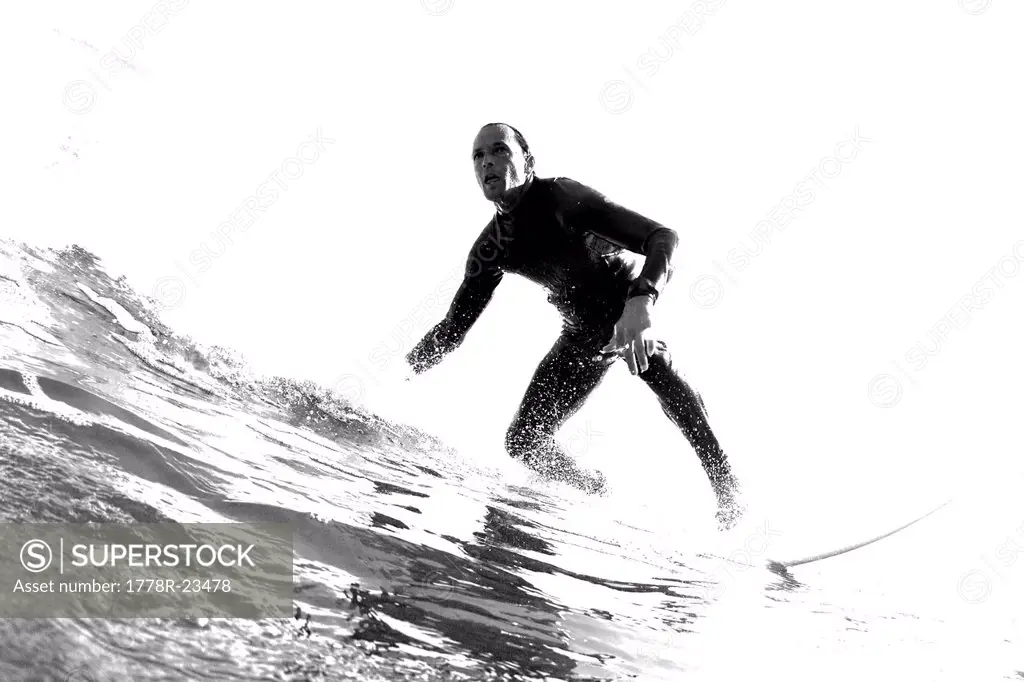 Black and white low angle perspective of a surfer riding a wave, .