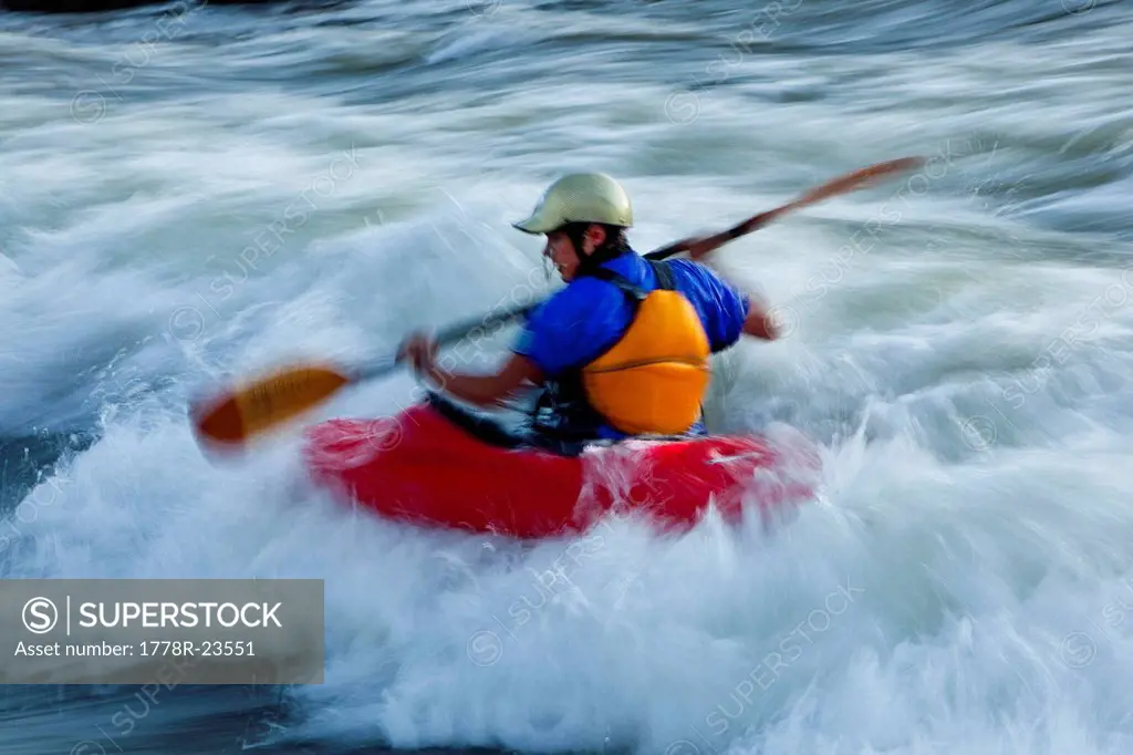 A female kayaker in a playboat battles the rapids on the Clark Fork River, Missoula, Montana.