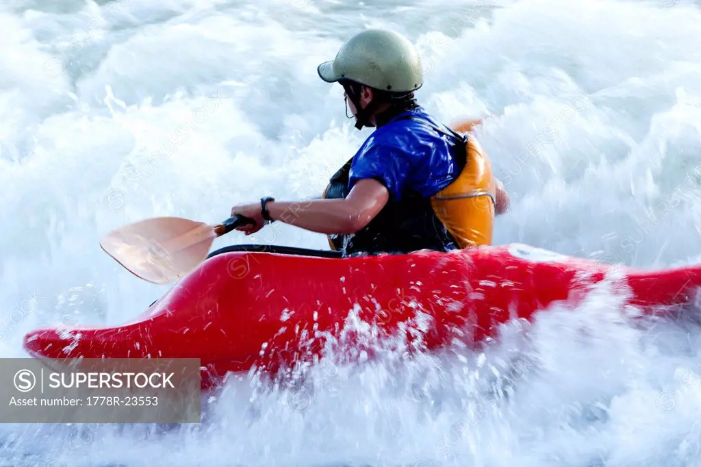 A female kayaker in a playboat battles the rapids of Brennan´s Wave on the Clark Fork River, Missoula, Montana.