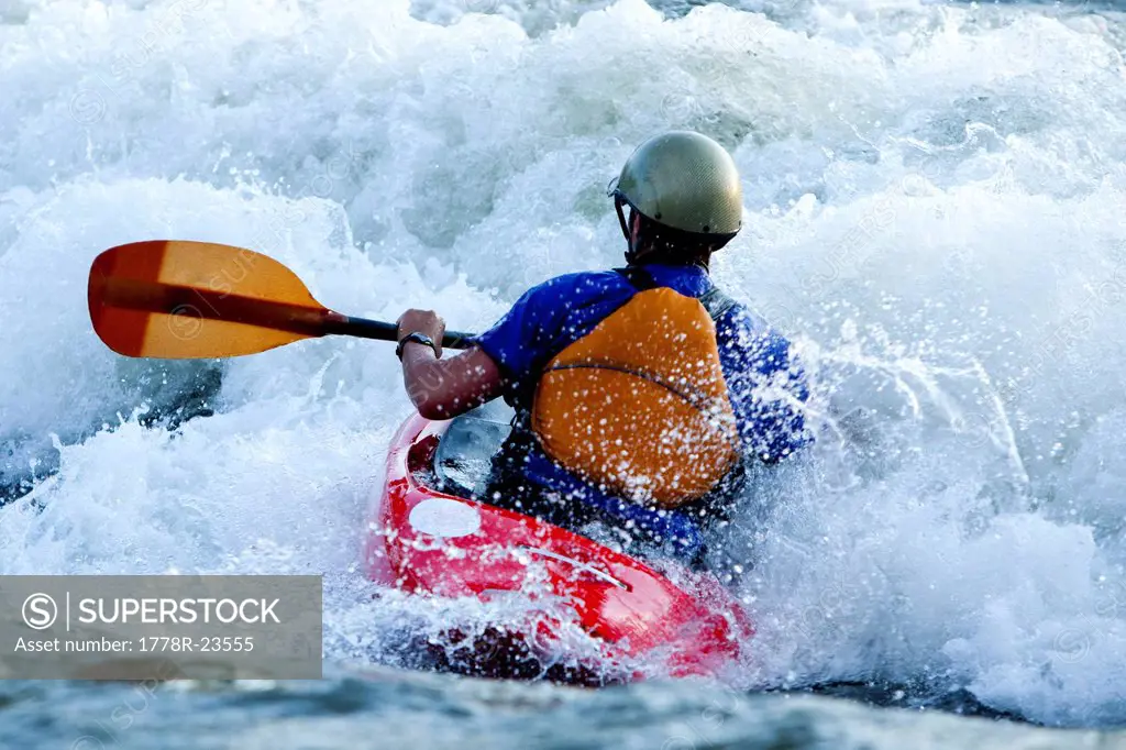 A female kayaker in a playboat battles the rapids of Brennan´s Wave on the Clark Fork River, Missoula, Montana.