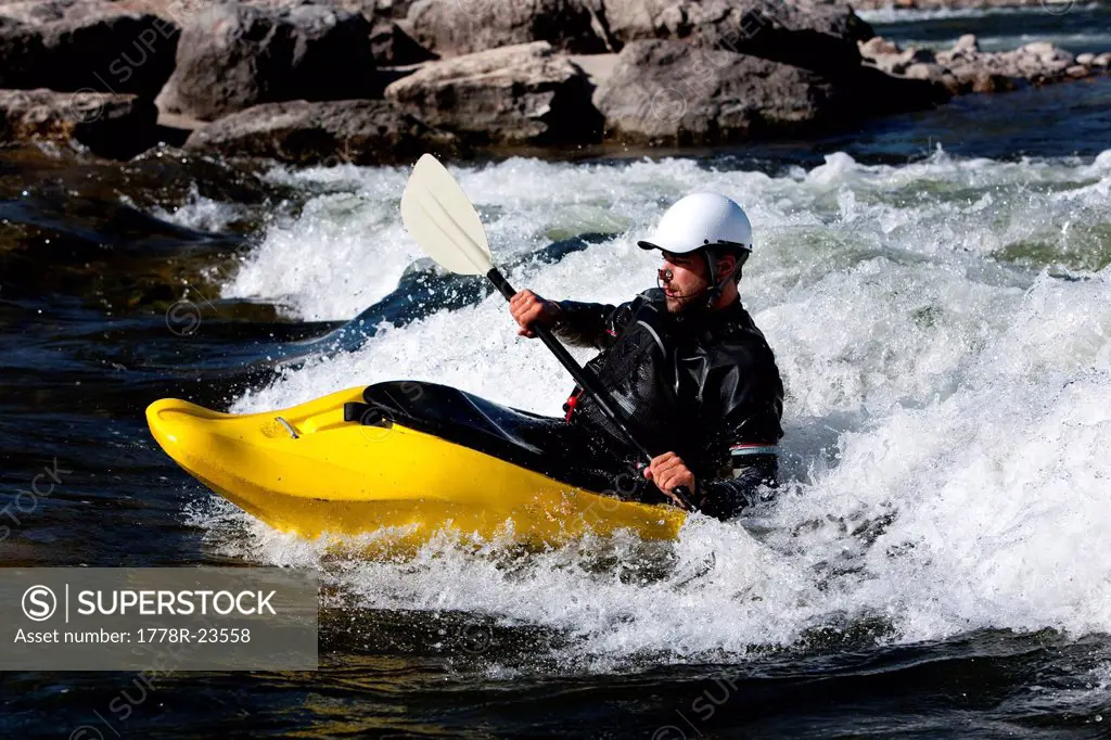 A male kayaker in a playboat rides the rapids of Brennan´s Wave, Missoula, Montana.