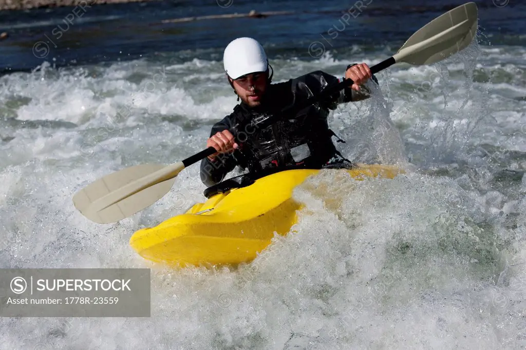 A male kayaker in a playboat paddles on the Clark Fork River, Missoula, Montana.