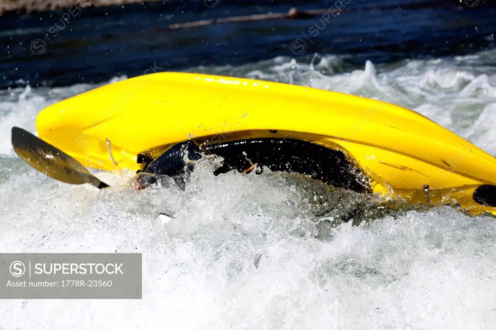 A male kayaker flips in a playboat rides the rapids of Brennan´s Wave, Missoula, Montana.