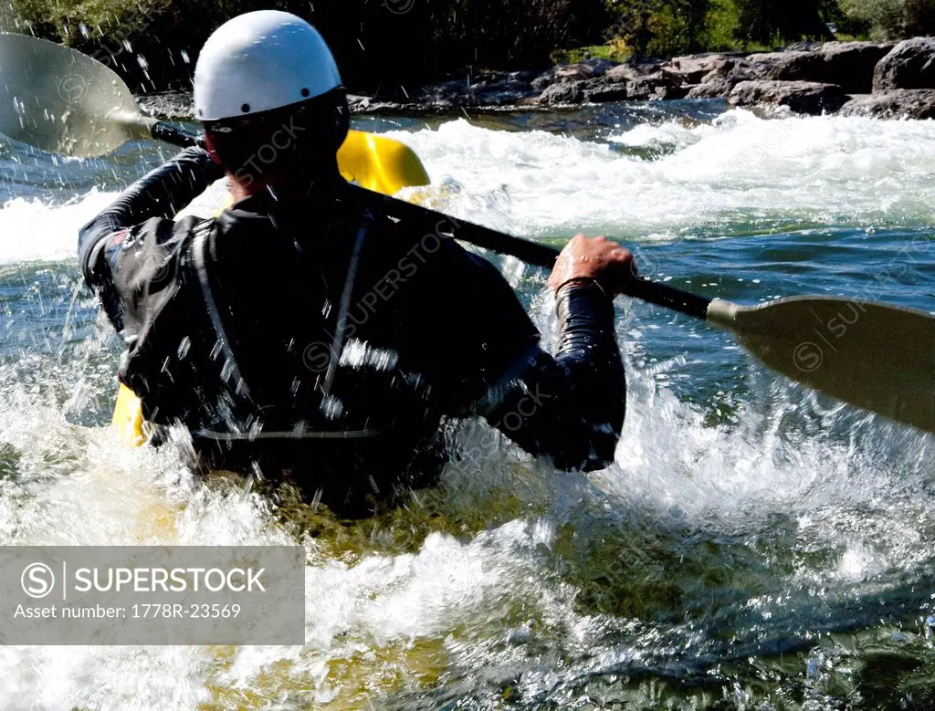 A male kayaker splashes into the rapids of the Clark Fork River in a playboat, Missoula, Montana.