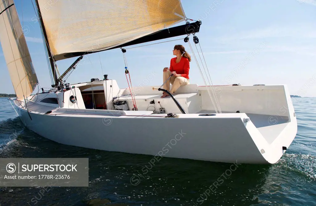 A woman enjoying a sunny day on board a daysailer on Casco Bay, Maine.