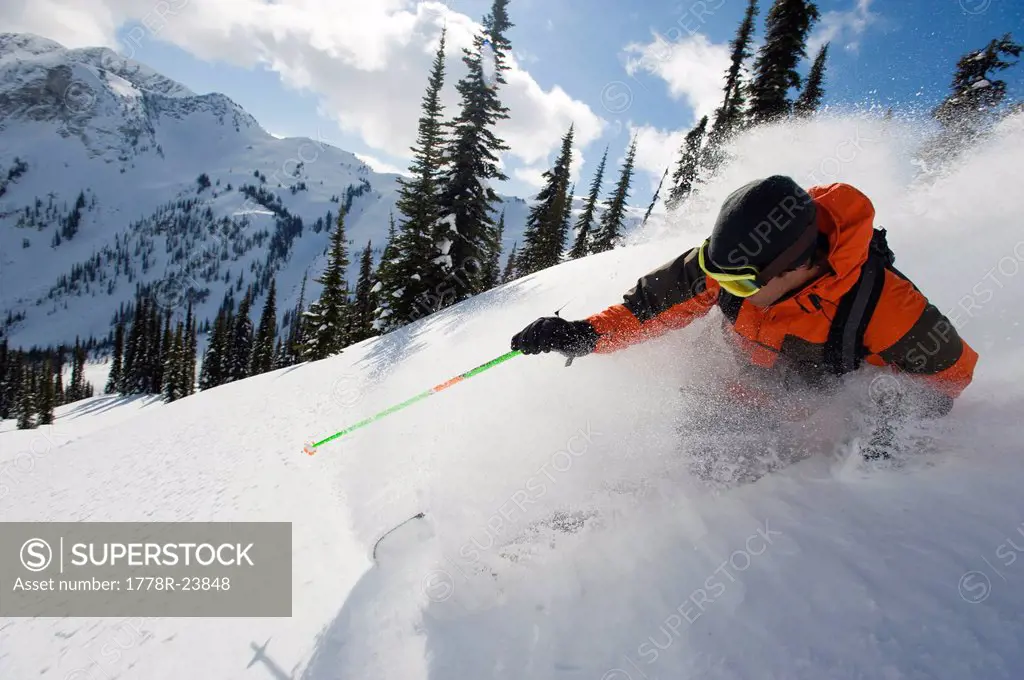 A young man skier skis the deep powder in the backcountry of the Selkirk Mountains, Canada.