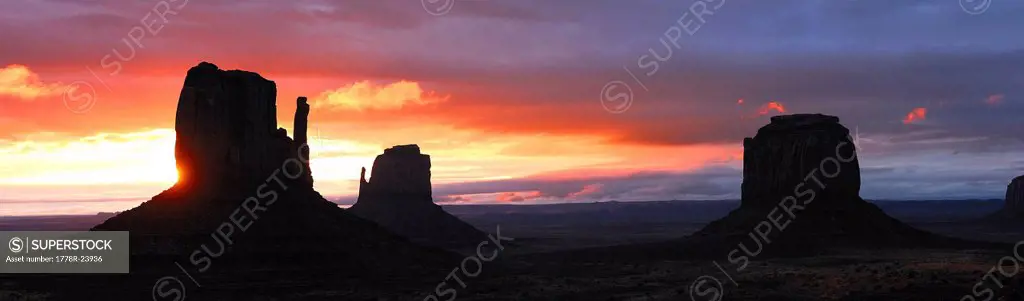 Sun setting behind rock formations at Monument Valley Navajo Tribal Park, Arizona, USA.
