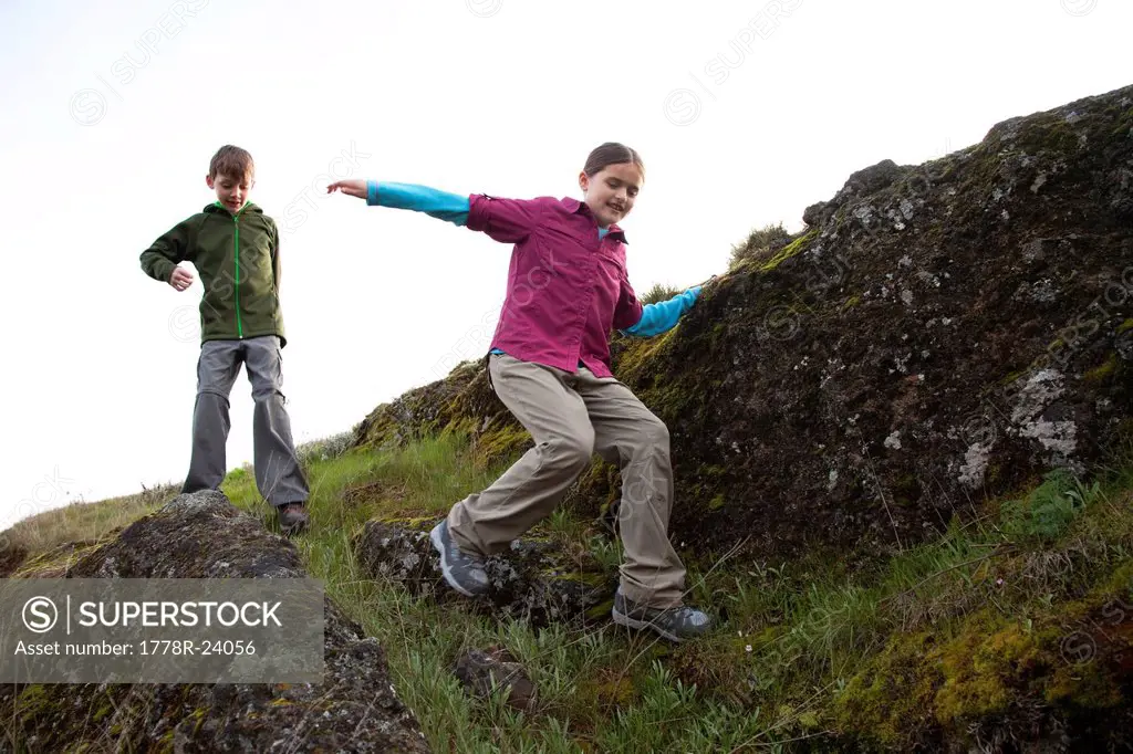 Kids scrambling down a grassy hillside.