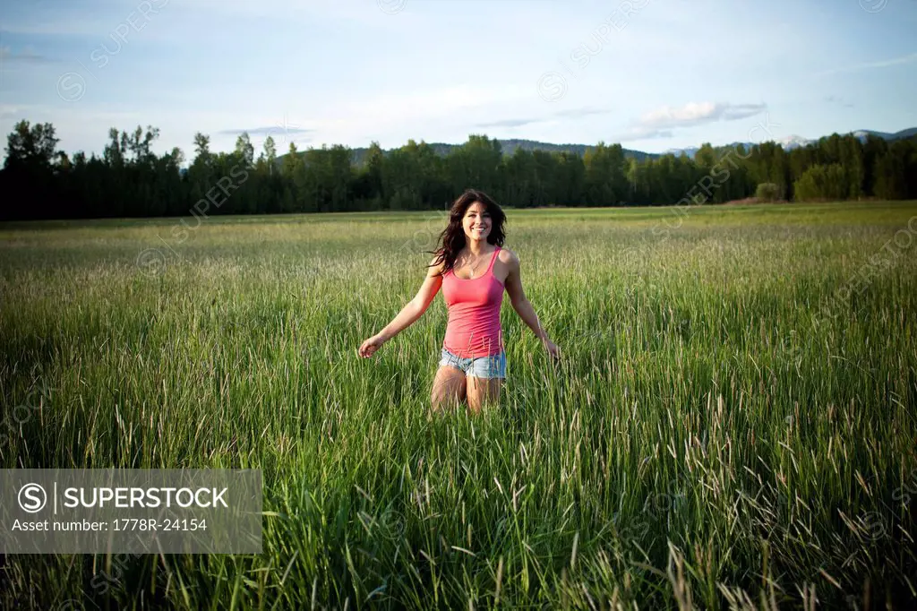 A girl twirls through tall grass on a sunny day in Idaho.