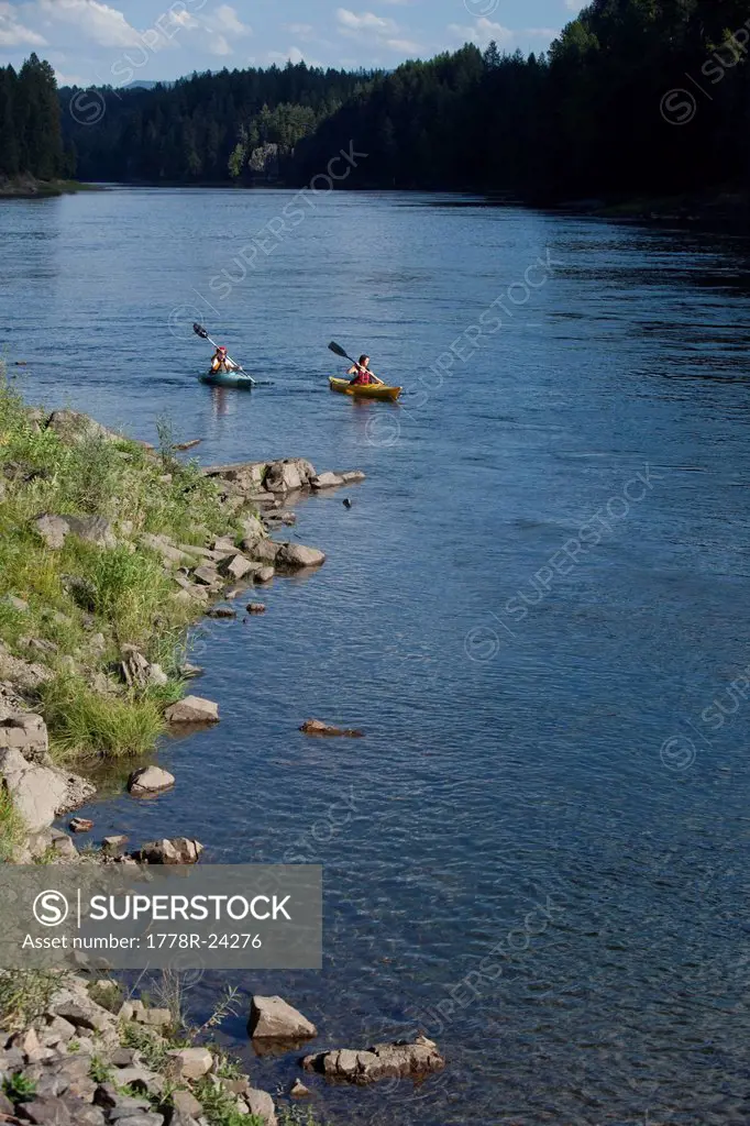 Young adult couple kayak on a beautiful summer day in Idaho.