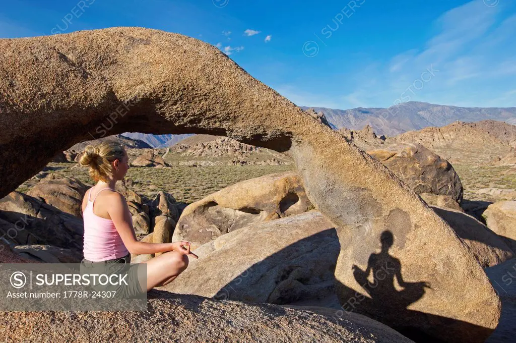 A shadow on a boulder of a woman practicing yoga.