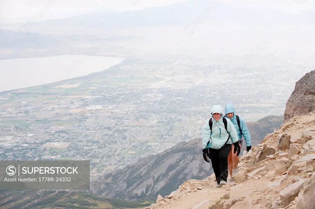 Two female hikers near the summit of Mt. Timpanogos, with the city of Pleasant Grove, UT in the background.