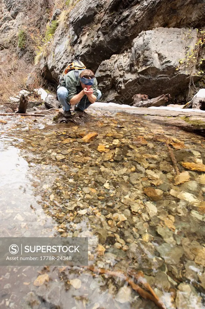 A young man drinks from a stream running through Big Cottonwood Canyon, Salt Lake City, UT.