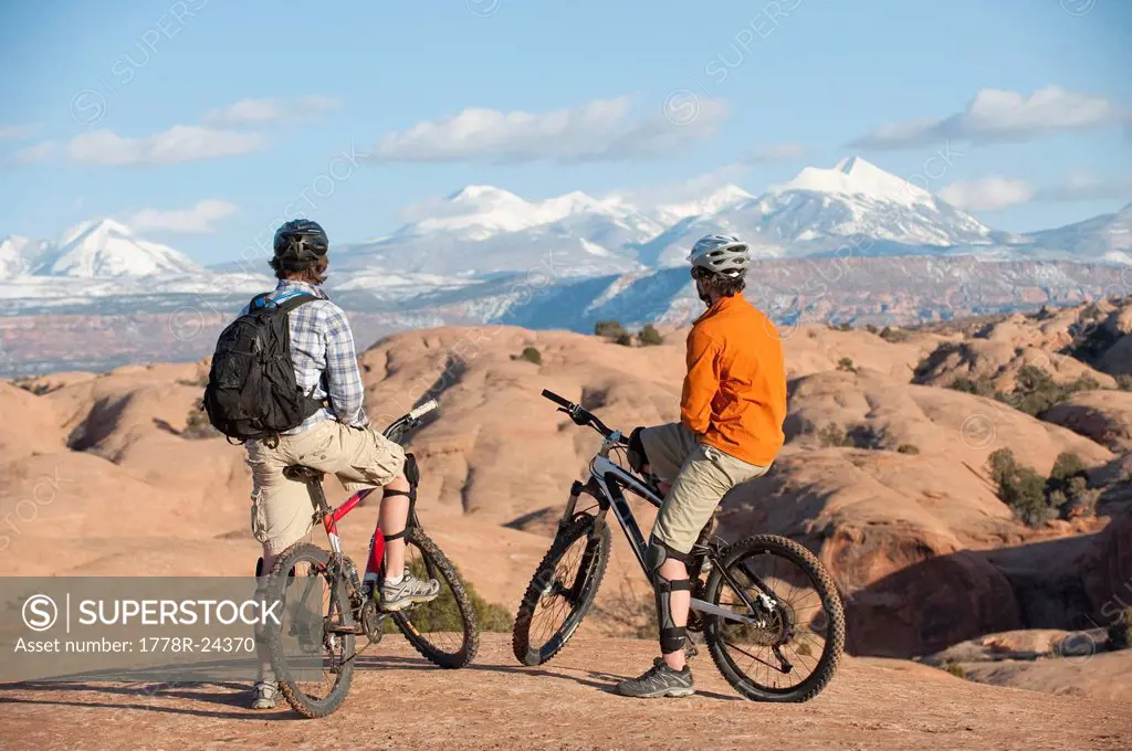 Two young men enjoy the view during a mountain bike trip on the Slickrock Trail, Moab, UT.