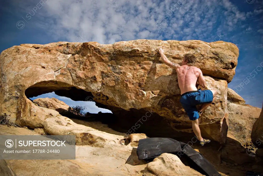 A young man reaches for a crimper hold while working out a boulder problem at the Lizard´s Mouth, a local climbing destination in Santa Barbara, CA