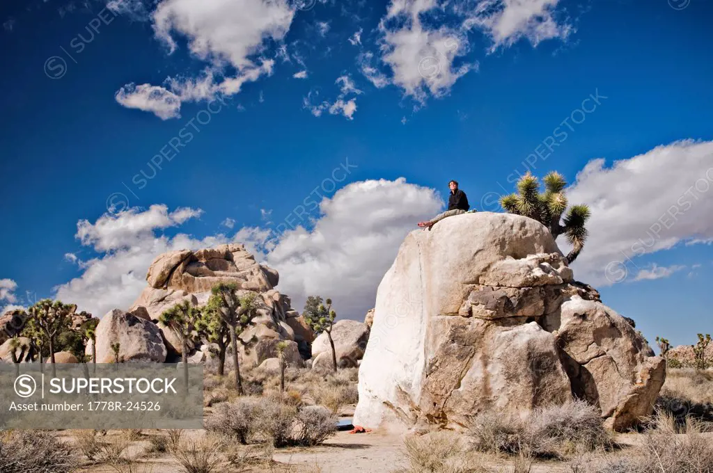 A young man sits on a lone bolder after climbing a route in Joshua Tree National Park.