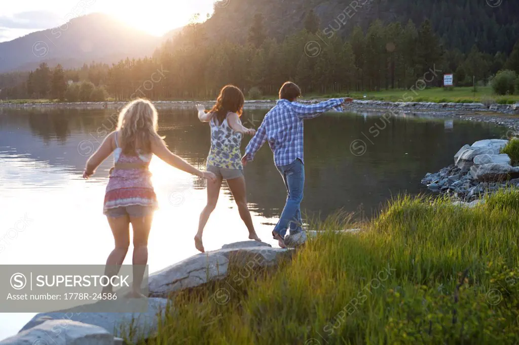 Three young adults walk along the shoreline at sunset in Idaho.