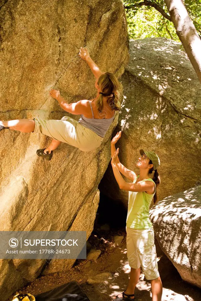 Spotted by a friend, a woman climbs a boulder problem in Utah´s Wasatch Mountains.