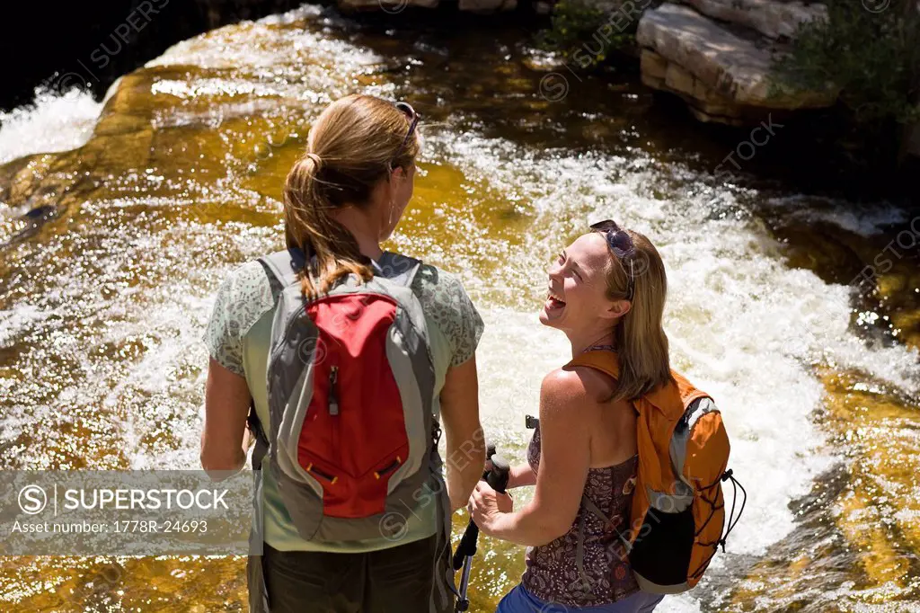 Two women talking and laughing during a hike along Utah´s Provo River.