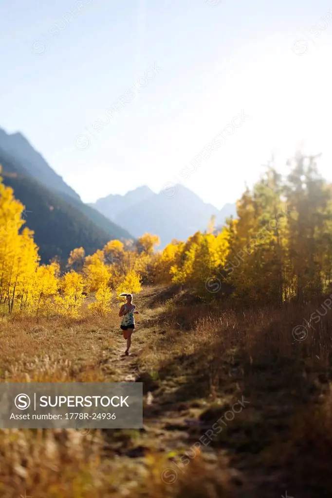 A young woman trail running in the fall colors.