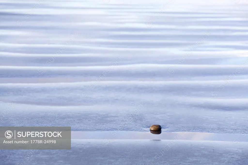 A small pebble lies on the beach among wavy sand ripples at Kalaloch Beach, Olympic National Park, Washington.