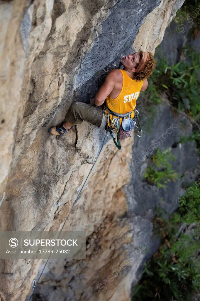 Climber strains at the crux of a difficult limestone route in China.