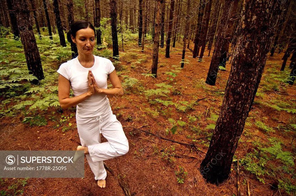 Woman in a yoga pose in a burned forest.