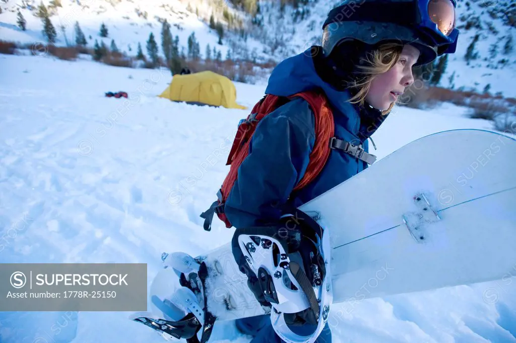 A boy prepares for a day of snowboarding in the California backcountry.