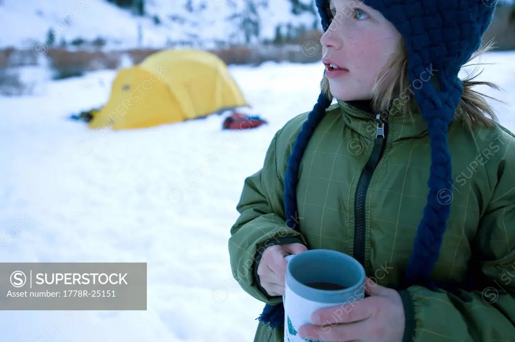 A boy drinks a cup of hot chocolate in the California backcountry.