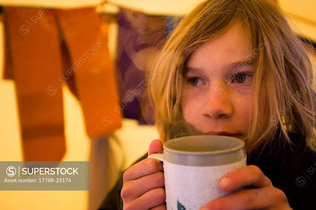 A boy enjoys a cup of hot chocolate in the backcountry of California.