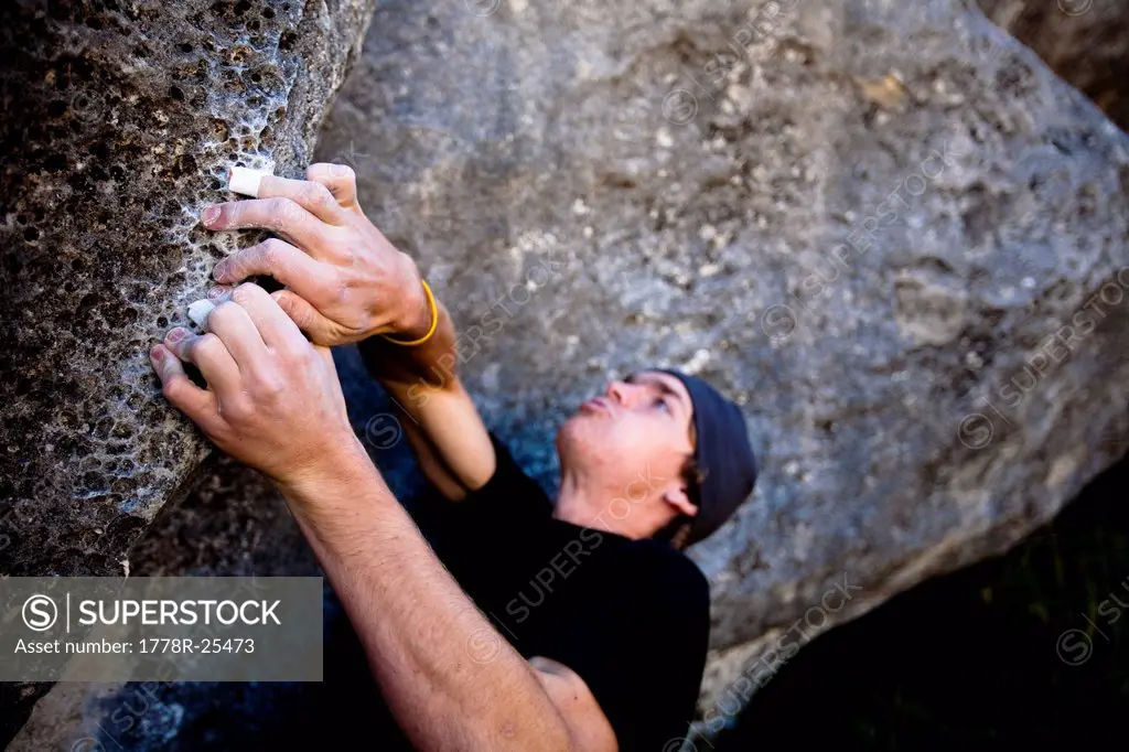 A male climber works a boulder problem called Toilet Brush V1 in Quantum Field, at Castle Hill, Canterbury, New Zealand.