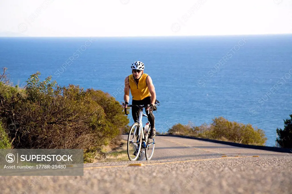 A cyclist in a yellow tank top rides his bike up Deer Creek road in Malibu, California.