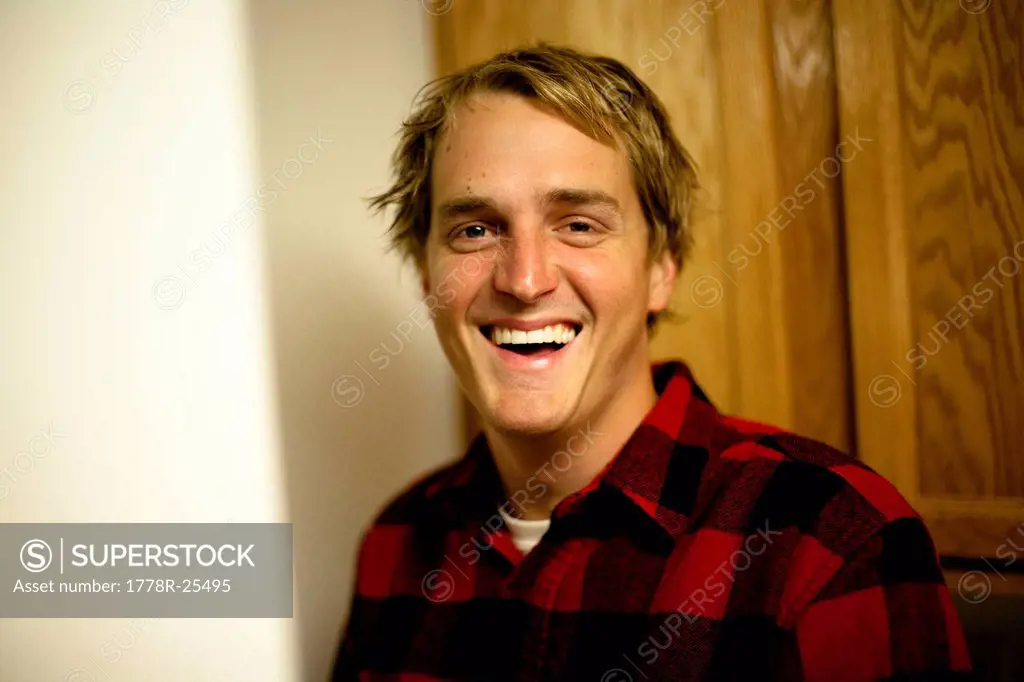 A young man wearing a red flannel jacket smiling at a camera in Camarillo, California.