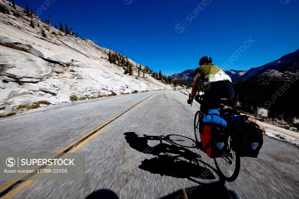 A young man rides his touring bike on the Tigoa Pass through Tuolumne Meadows in Yosemite, California.